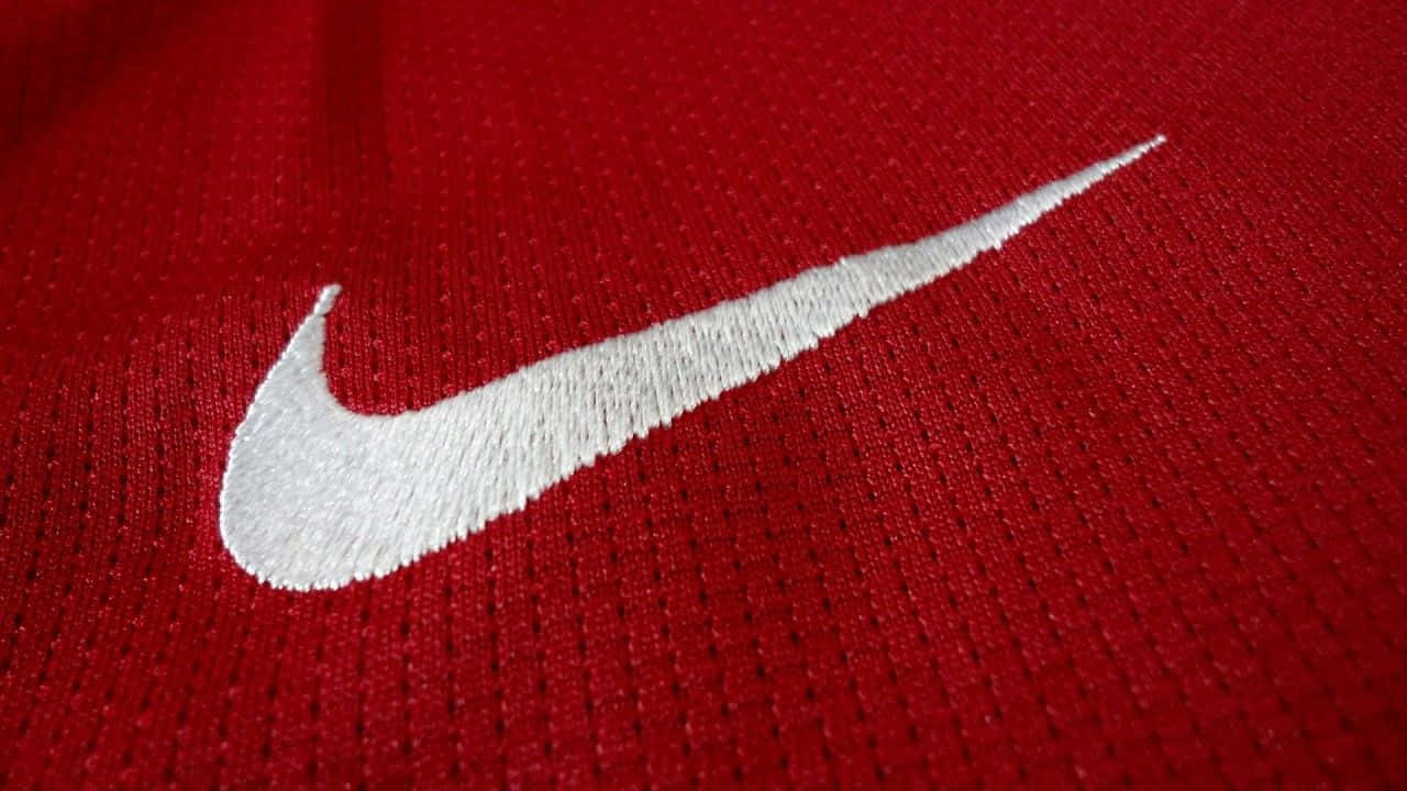 以經典紅色Nike展現你的風格 壁紙 — 白色刺繡Nike標誌在質感紅色運動布料上的特寫。