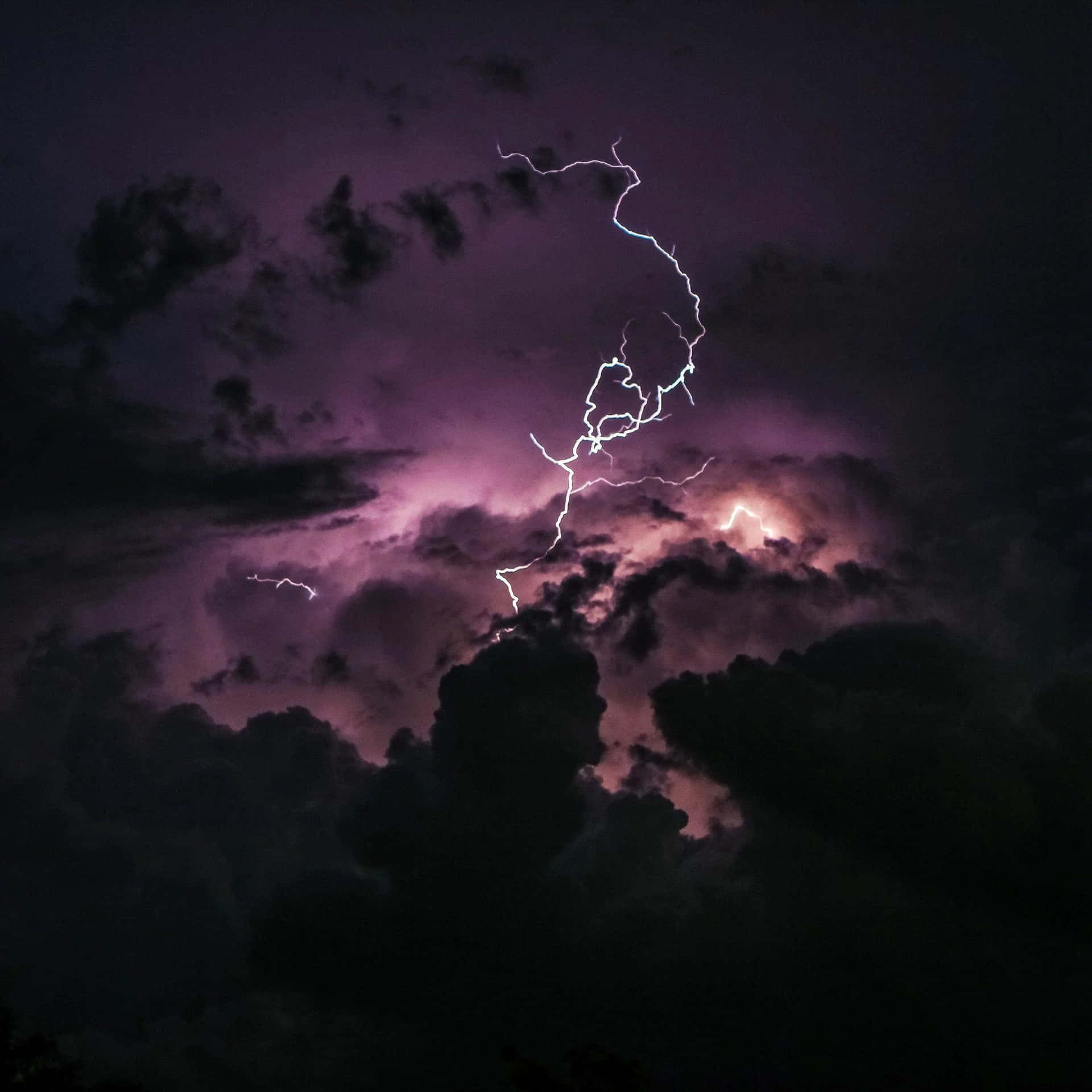 夜晚被明亮閃電照亮的紫色暴風雨雲。