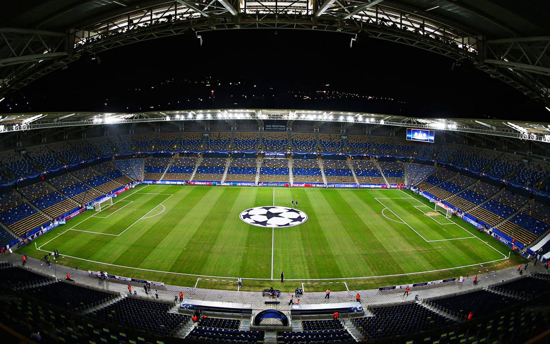 夜間照明的一個大型空足球場，場地上有UEFA Champions League標誌。