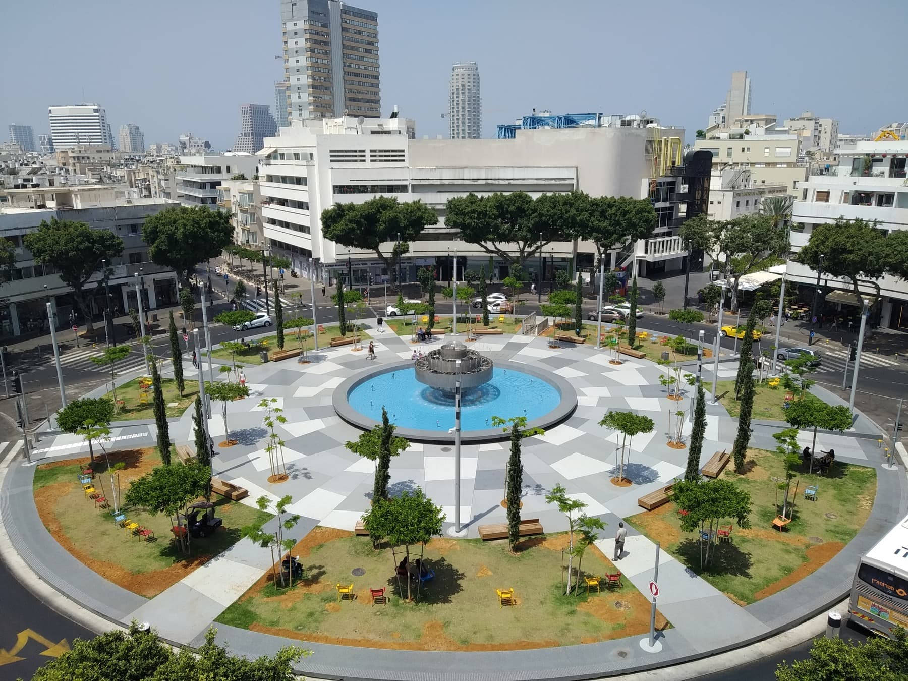 圓形城市廣場，設有噴泉、樹木和長椅，周圍環繞建築物。