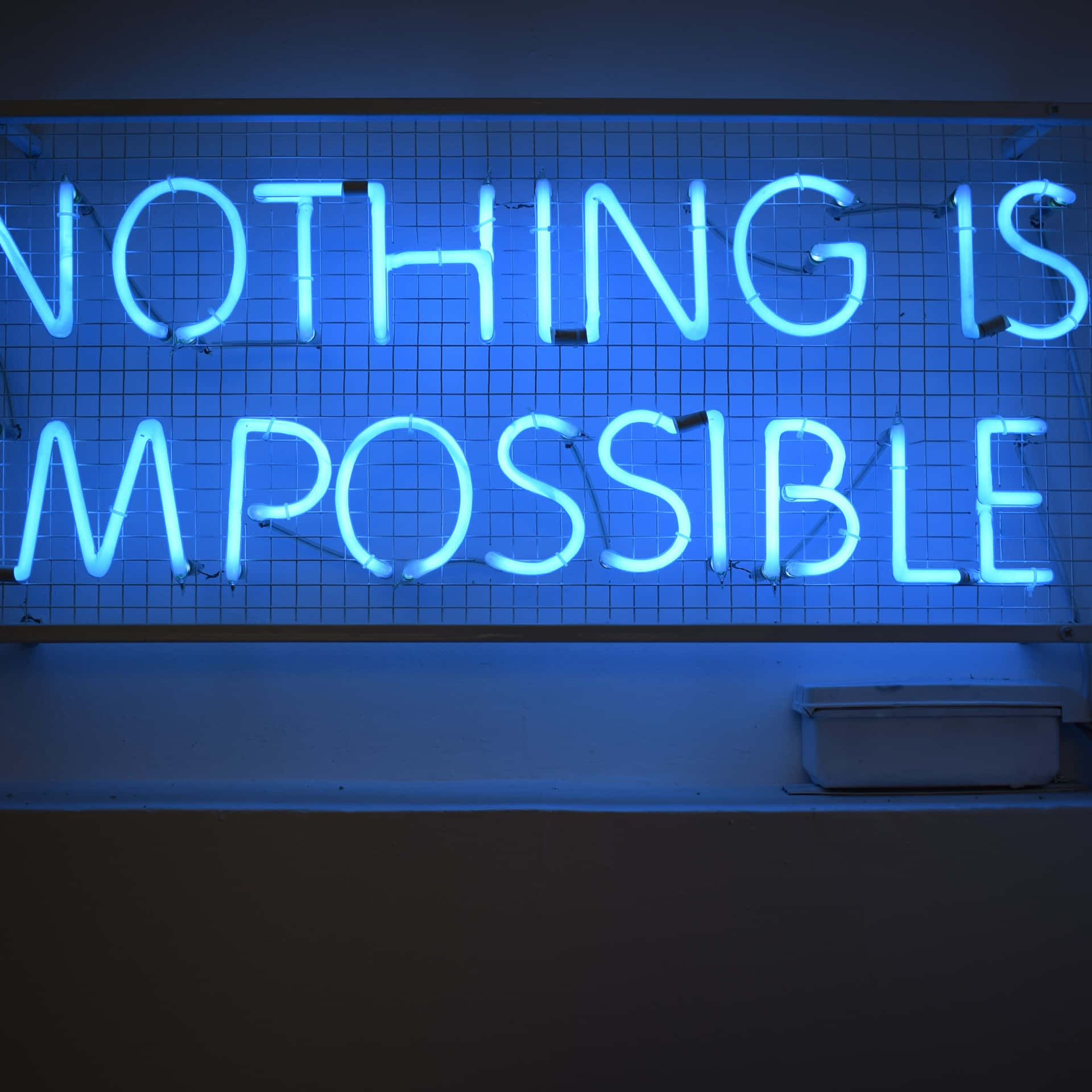 藍色霓虹燈牌在網格牆上寫著 nothing is impossible。