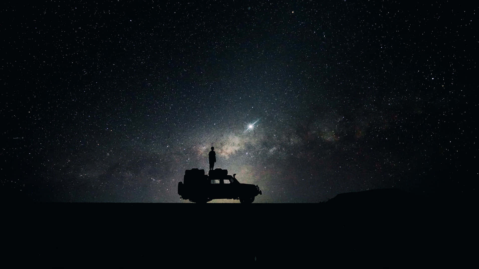 星空下車輛上的人影剪影與銀河