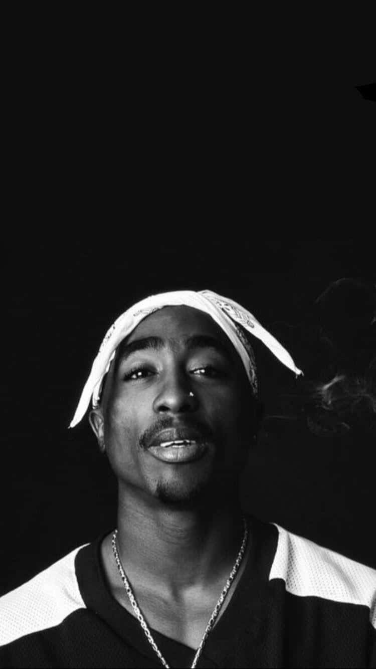 Tupac Shakur 在黑白照片中微笑抽煙。