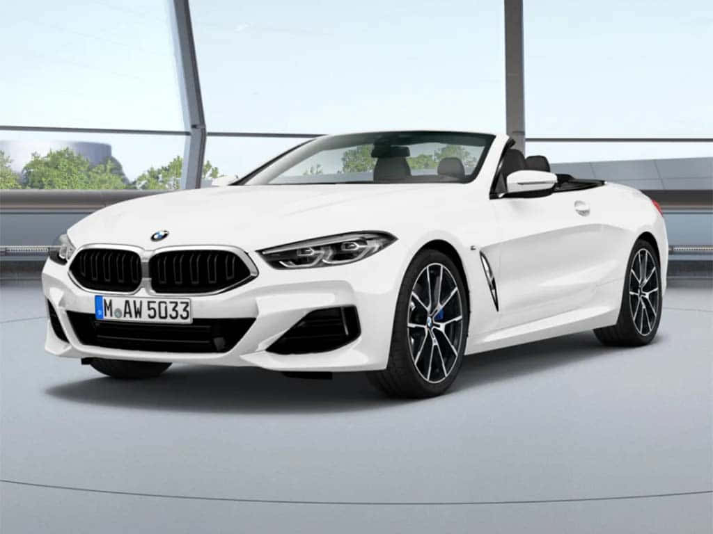 以這款BMW M5展現你的風格 壁紙 — 一輛純白色的寶馬開篷跑車在明亮的攝影棚燈光下閃閃發光，背景是現代玻璃建築。