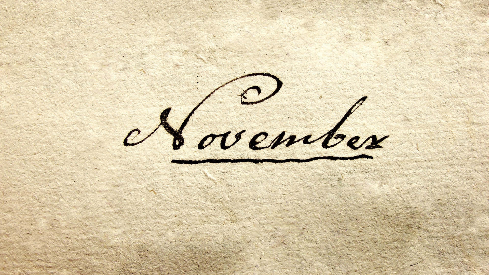 在紋理米色紙上以黑色墨水手寫的「November」一詞。
