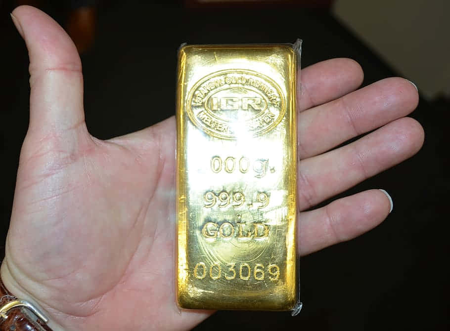 手握住一塊刻有標記嘅1000g純金金條。