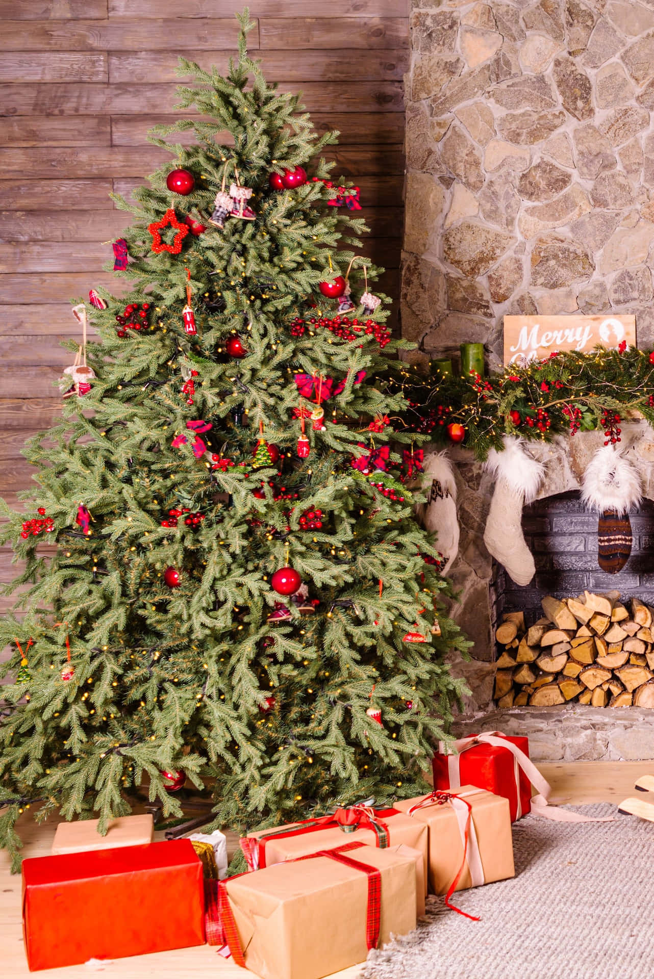 裝飾好的聖誕樹，旁邊有禮物和石壁爐，下面有襪子。