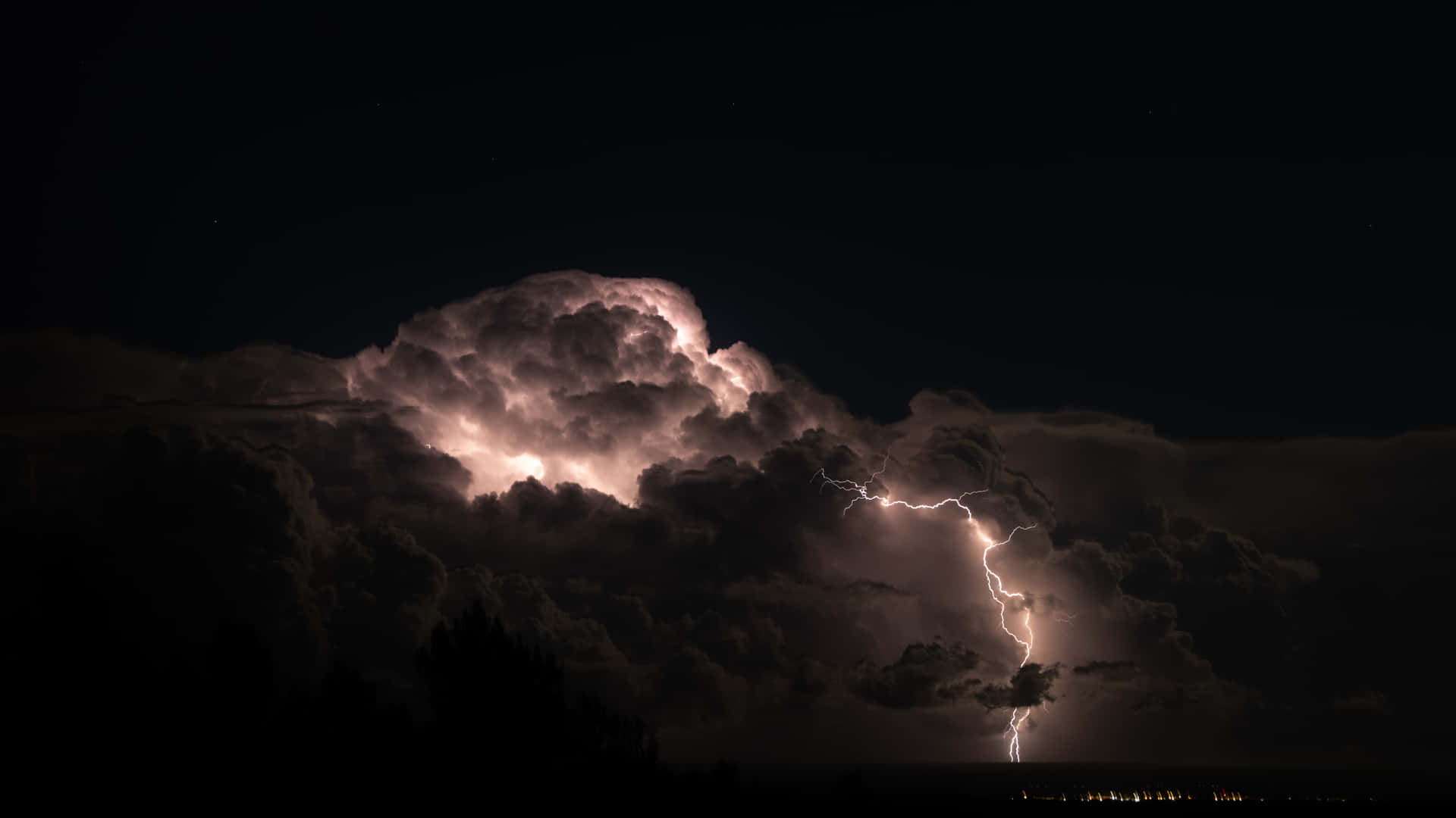 明亮的閃電照亮了夜晚黑暗景觀上的暴風雲。