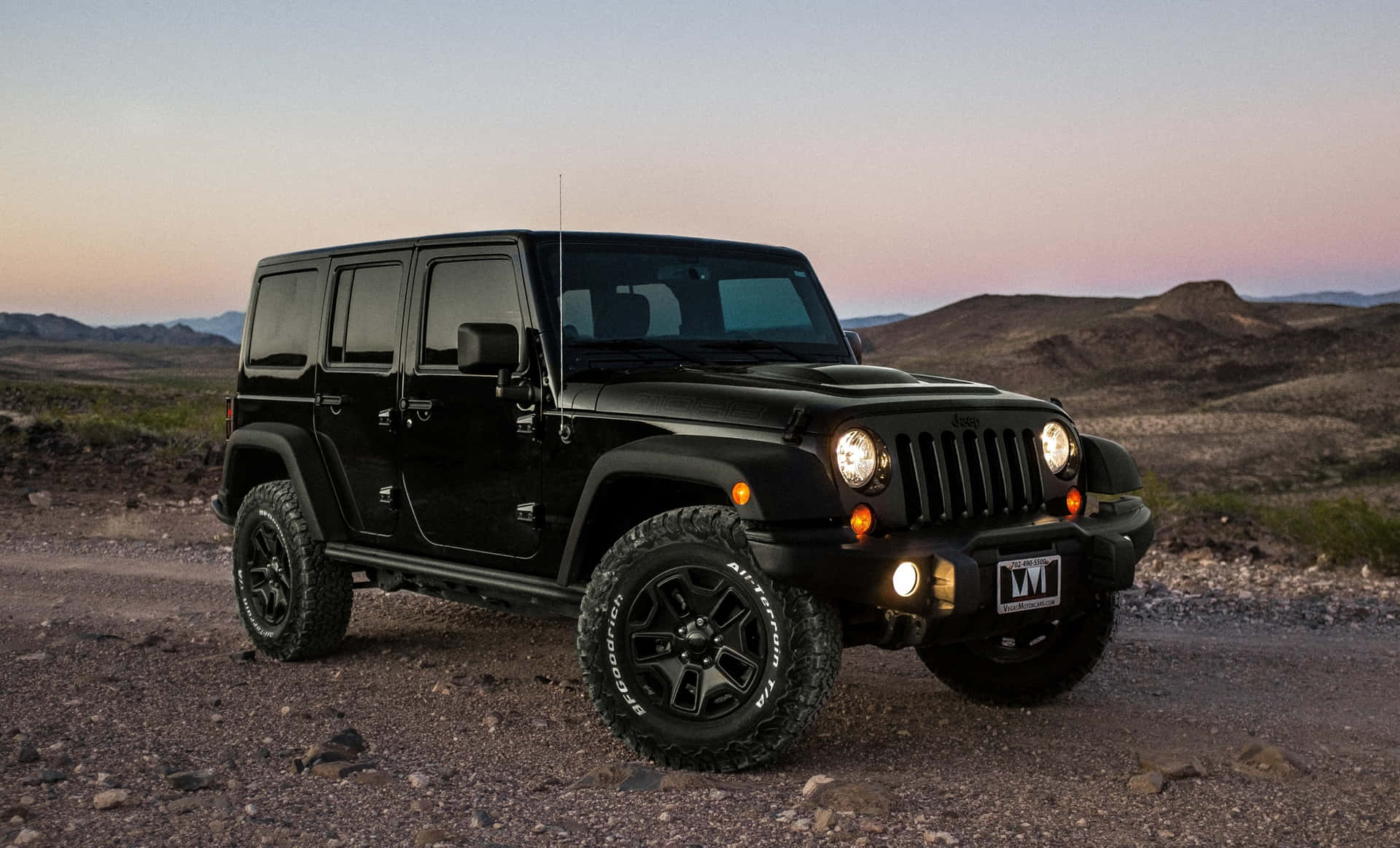 黑色Jeep Wrangler停在沙漠小徑上，夕陽時分