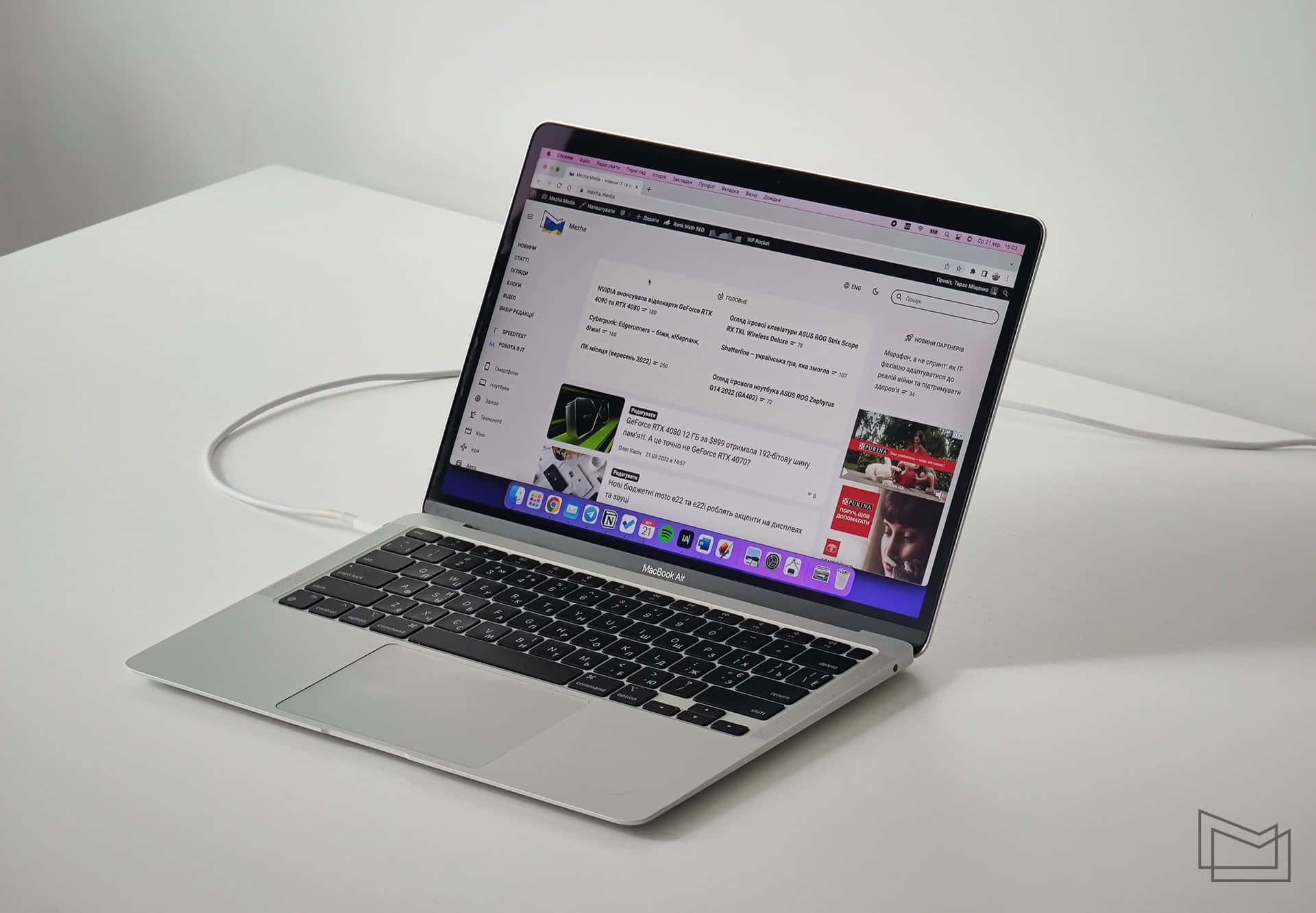 以風格完成工作，選擇 MacBook 壁紙 — 一部時尚的銀色 MacBook Air 打開放在白色桌子上，顯示帶有西里爾文字和產品圖片的網頁瀏覽器。