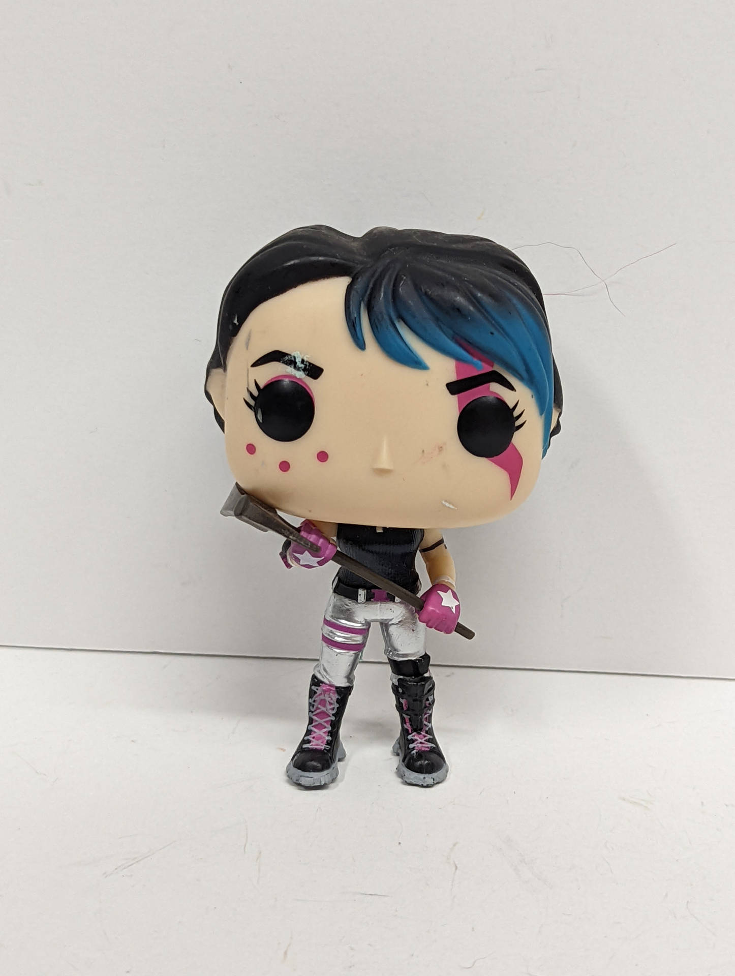 Funko Pop! 公仔，描繪一個擁有藍色和黑色頭髮及粉紅色臉部彩繪的女性角色，手持武器。