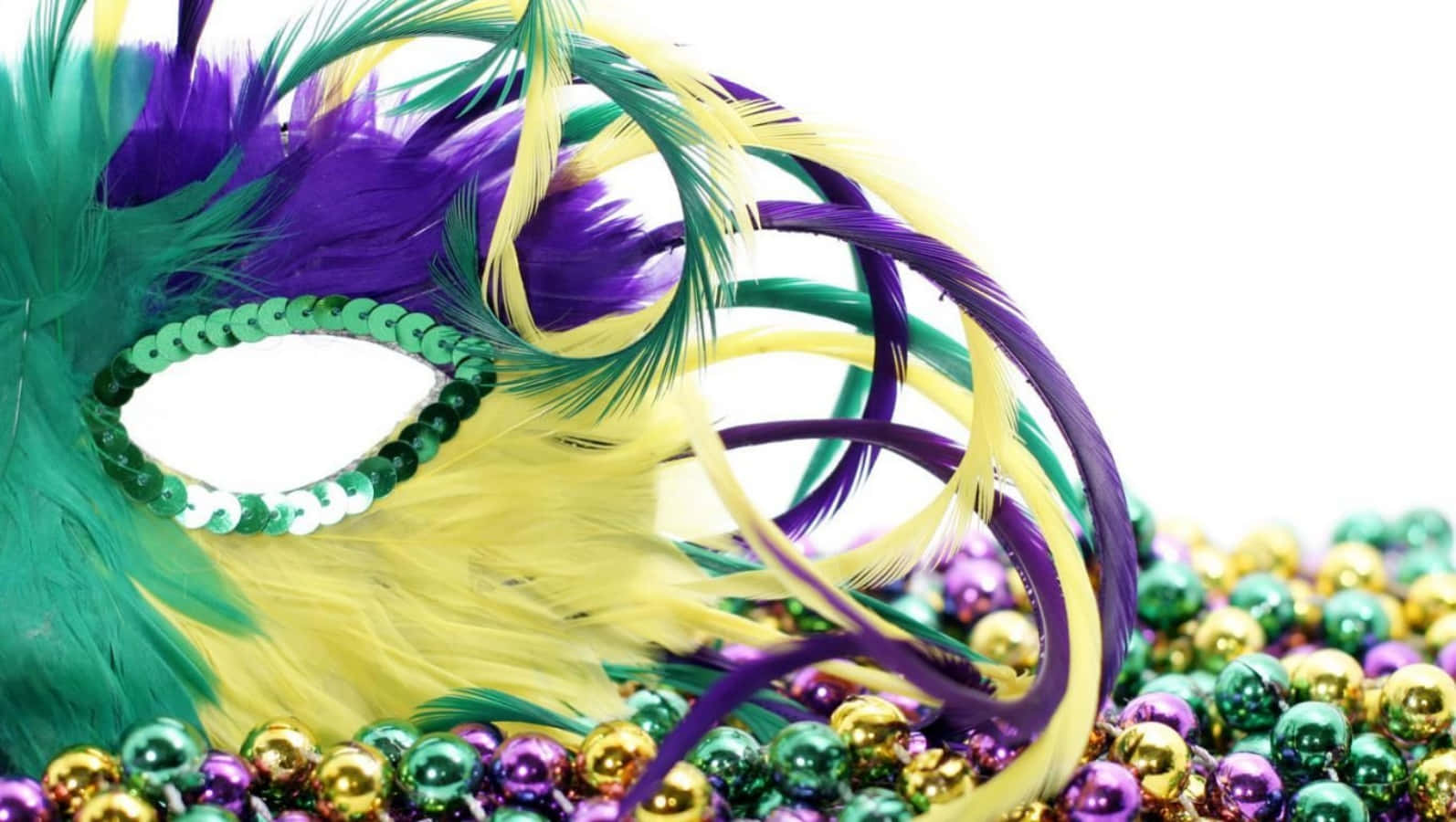 以風采慶祝嘉年華 壁紙 — 一個充滿活力的狂歡節面具，飾有紫色、綠色和金色的羽毛和珠子，放在一堆節日金屬珠子上。