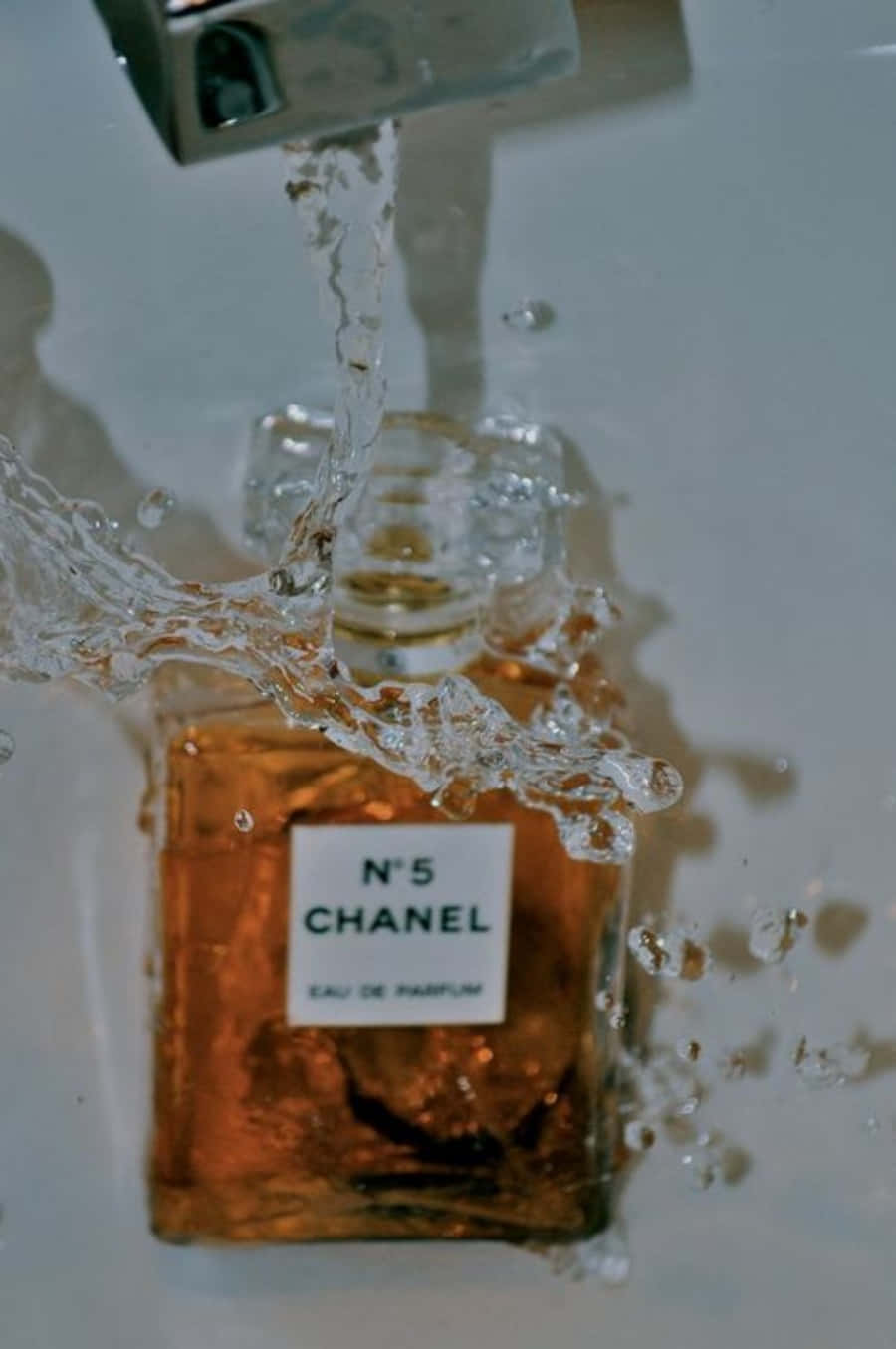 以香奈兒的優雅展現最佳風采 壁紙 — Chanel N5 香水瓶浸在浴缸中，水流過其玻璃表面。