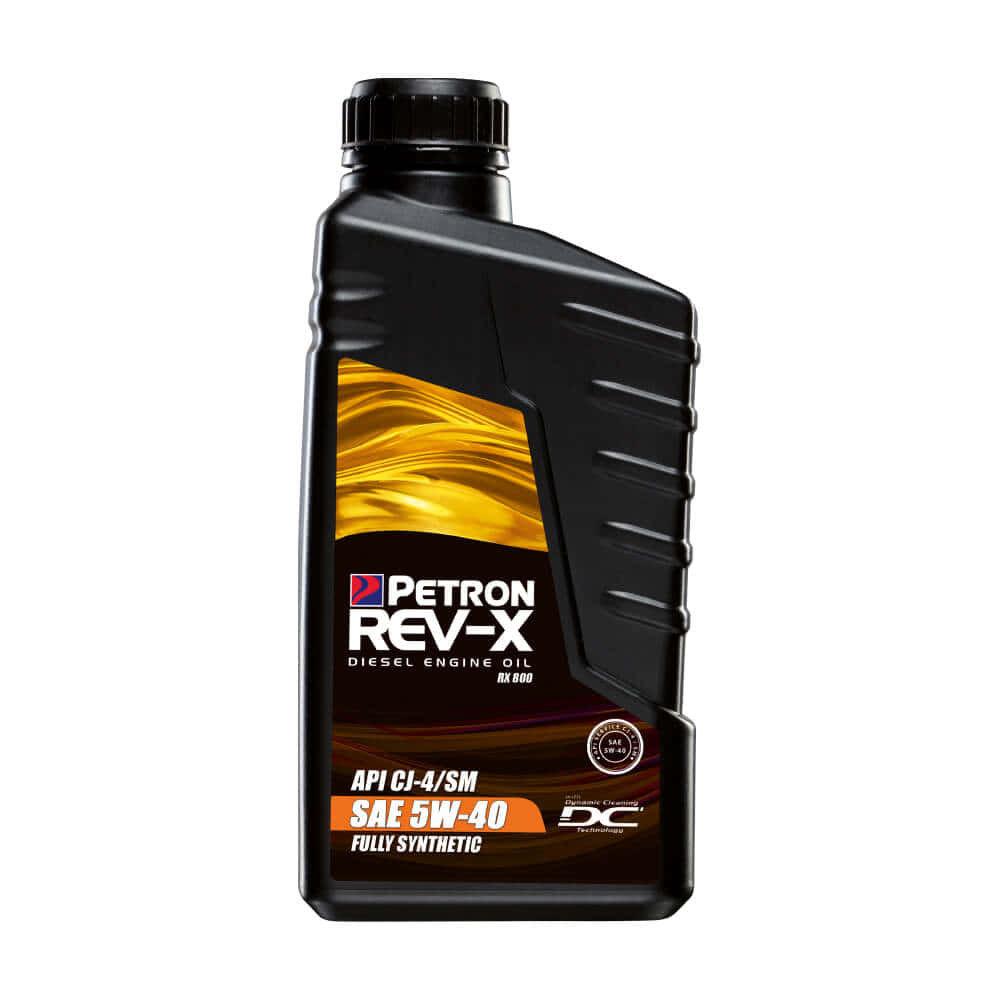 以高級機油延長引擎壽命 壁紙 — 黑色Petron Rev-X柴油引擎機油瓶，帶有金色液體漩渦標籤，白色背景。