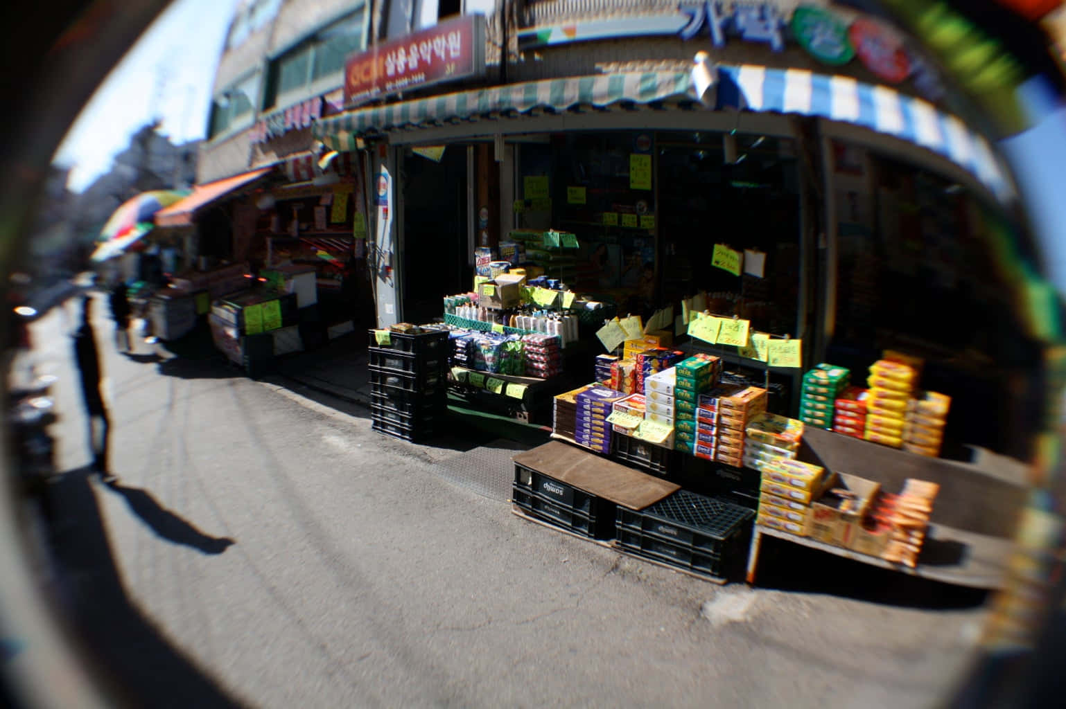 魚眼視角下的熱鬧街市，充滿色彩繽紛的商品和店舖門面。