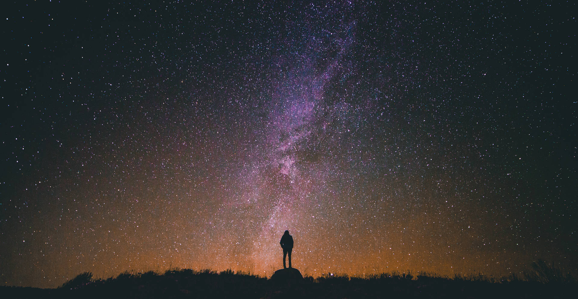 人站在山丘上，在星空下，有銀河