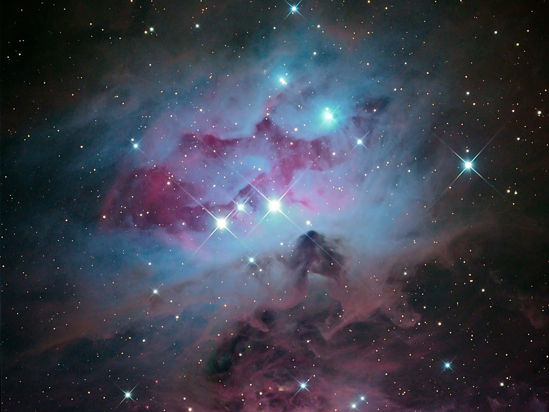在深空中，明亮的星辰照耀下，充滿活力的粉紅和藍綠色星雲。