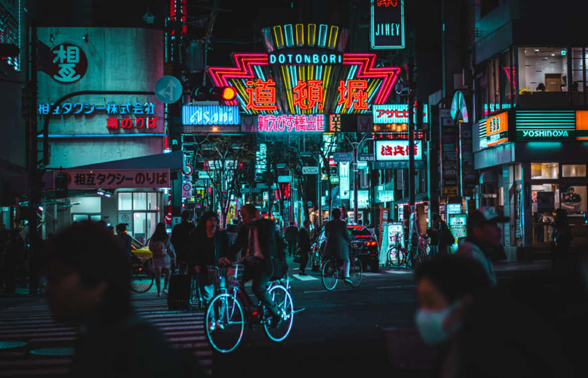 霓虹燈照亮夜晚的東京街道，有騎單車者和行人。