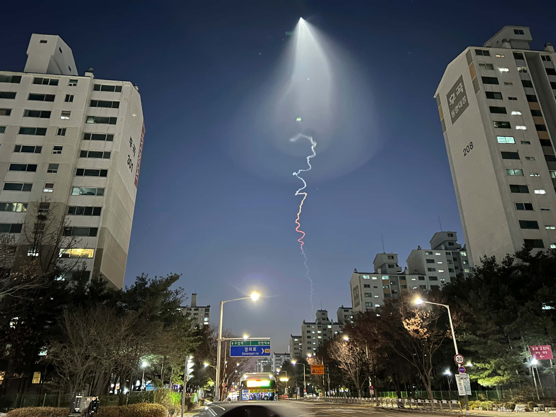 垂直光跡照亮城市建築之間的夜空。
