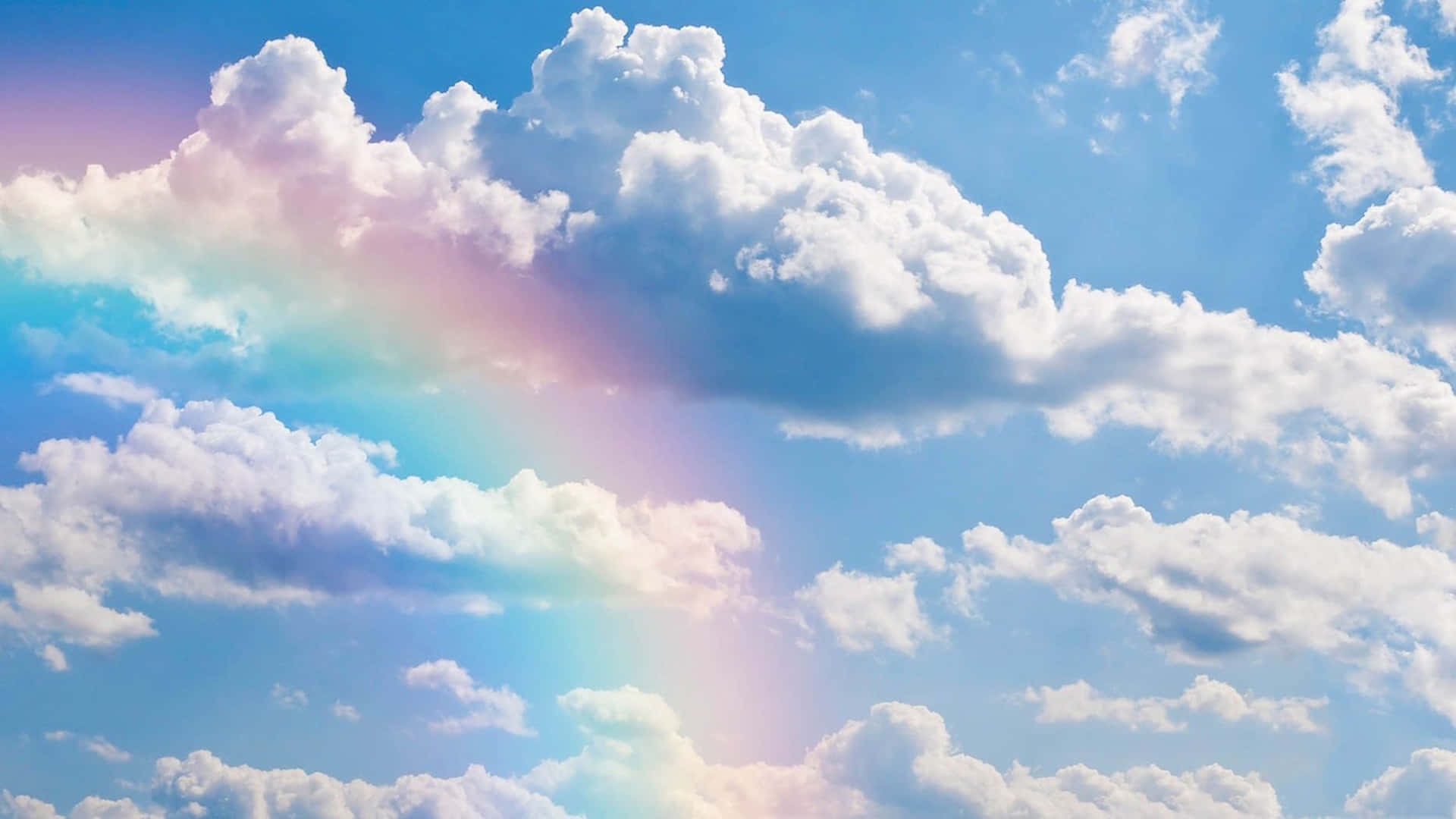 仰望雲朵，尋找靈感 壁紙 — 一道鮮豔的彩虹優雅地彎過蓬鬆的白雲，映襯著明亮的藍天。