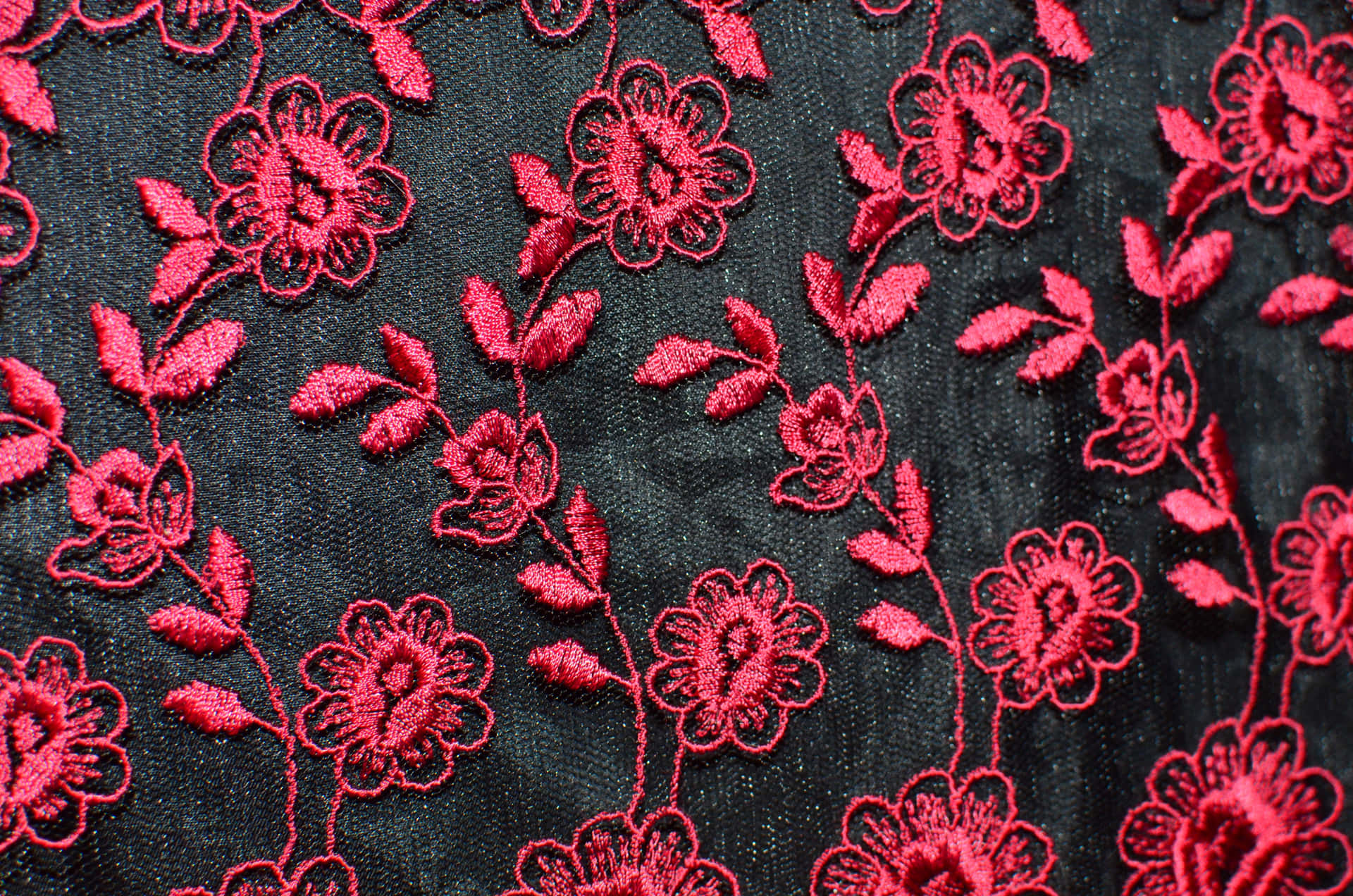 深色布料上的紅色花卉刺繡，帶有細緻針腳