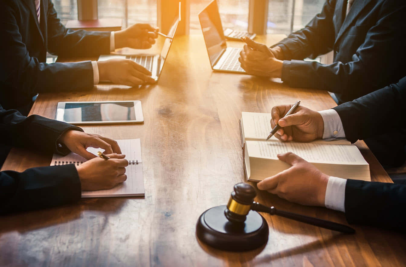 穿著西裝的法律專業人士在木桌上使用筆記型電腦和法官槌工作。