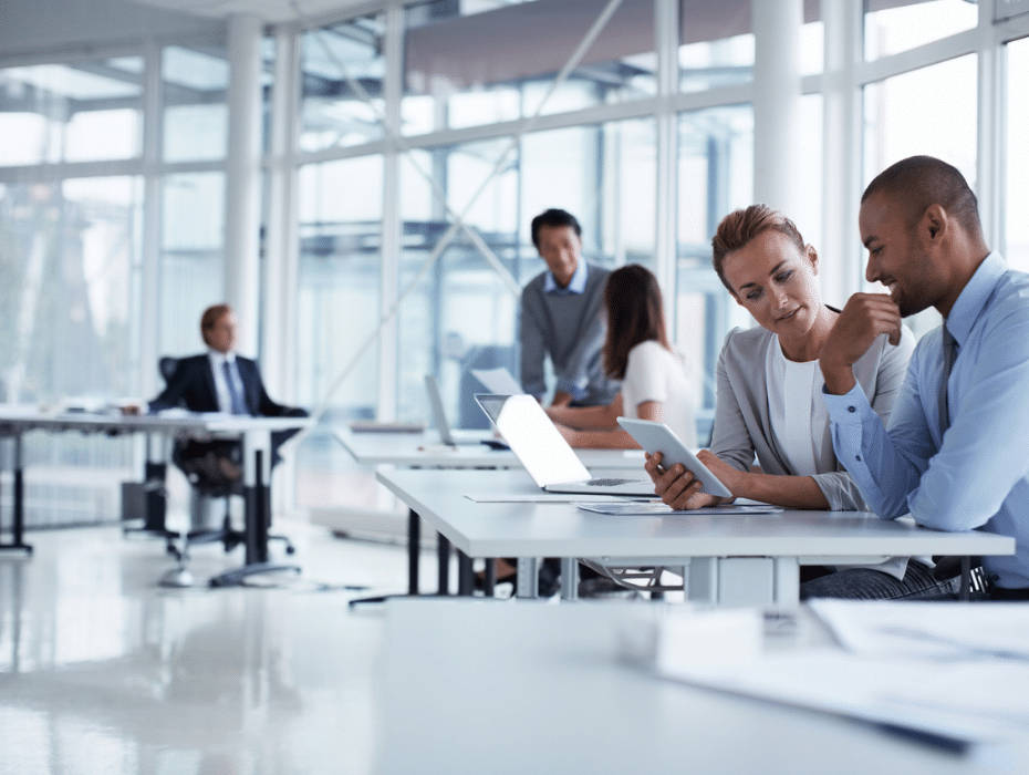 企業公司商務會議 壁紙 — 兩位專業人士在一個明亮現代、設有大窗戶的開放式辦公室中，專注地協作使用平板電腦。