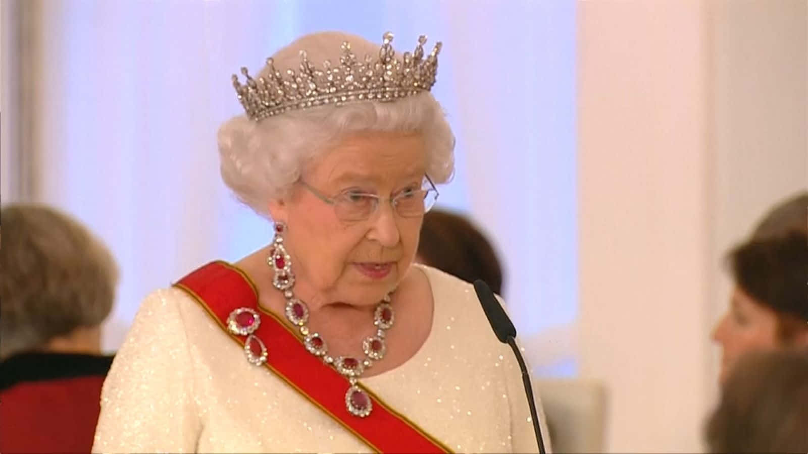 Queen Elizabeth 桌布 壁紙 — 伊利沙伯二世女王佩戴閃爍的頭飾和紅寶石飾帶，在室內的正式活動中發言。