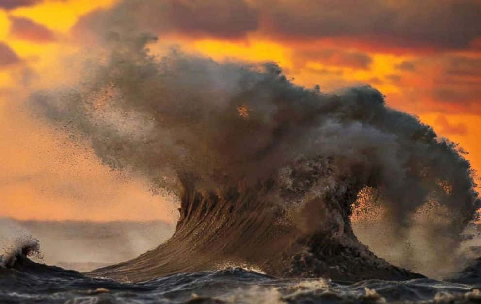 日落時分，巨大的海浪伴隨著霧氣和火熱的天空破碎。
