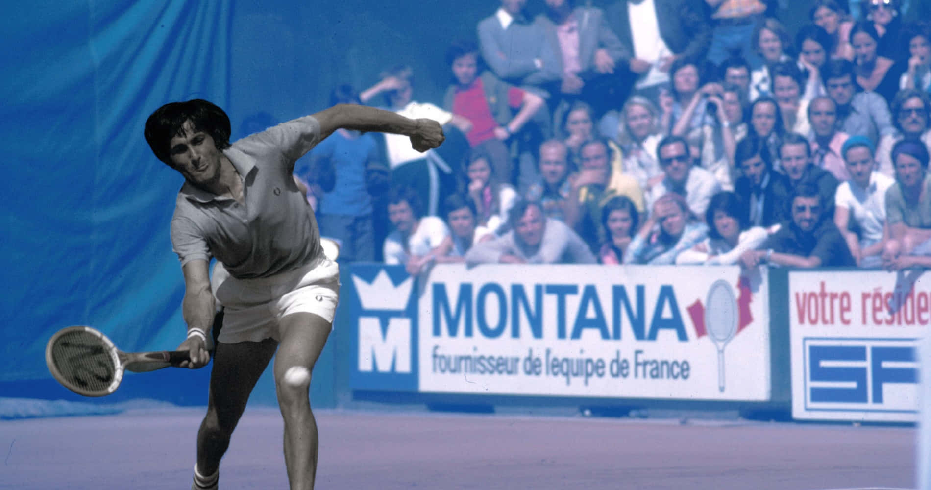 伊利耶·納斯塔塞 - 羅馬尼亞網球冠軍 壁紙 — 一名男性網球選手在藍色球場上揮拍，人群在贊助商橫幅後觀看。