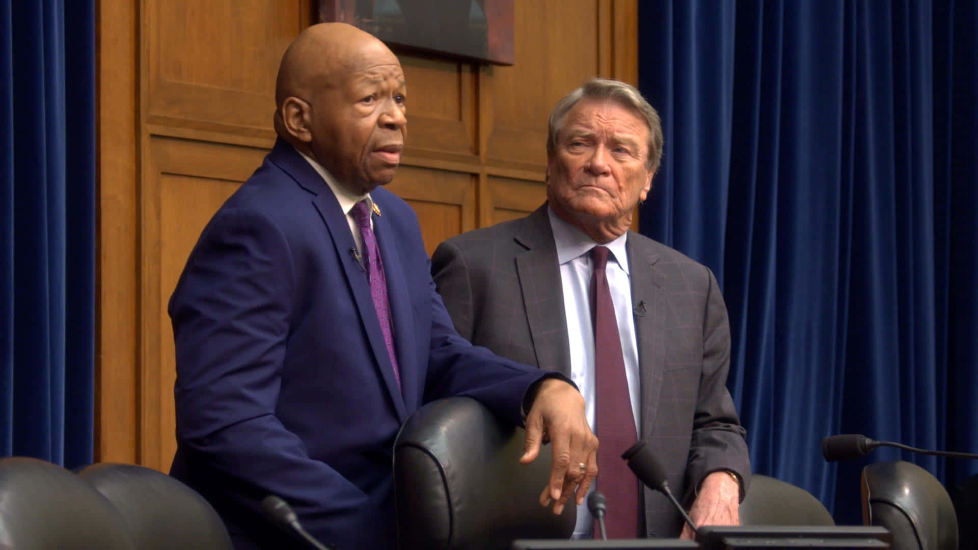 兩名身穿西裝的男子在正式活動中站在講台上。