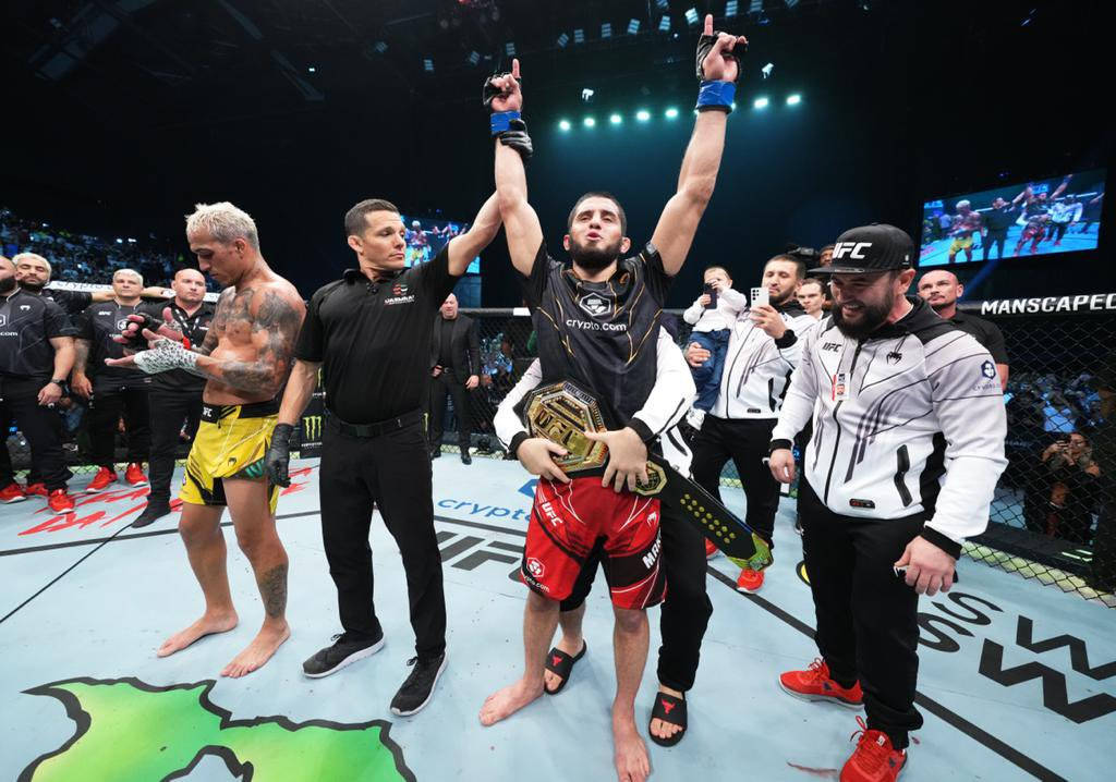 MMA拳手在八角籠中手持冠軍腰帶慶祝勝利。