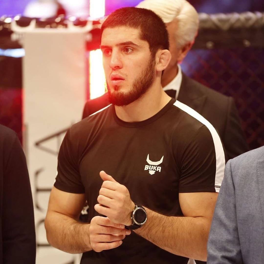 身穿帶白色條紋黑色襯衫的 MMA 拳手在八角籠內握緊拳頭站立。