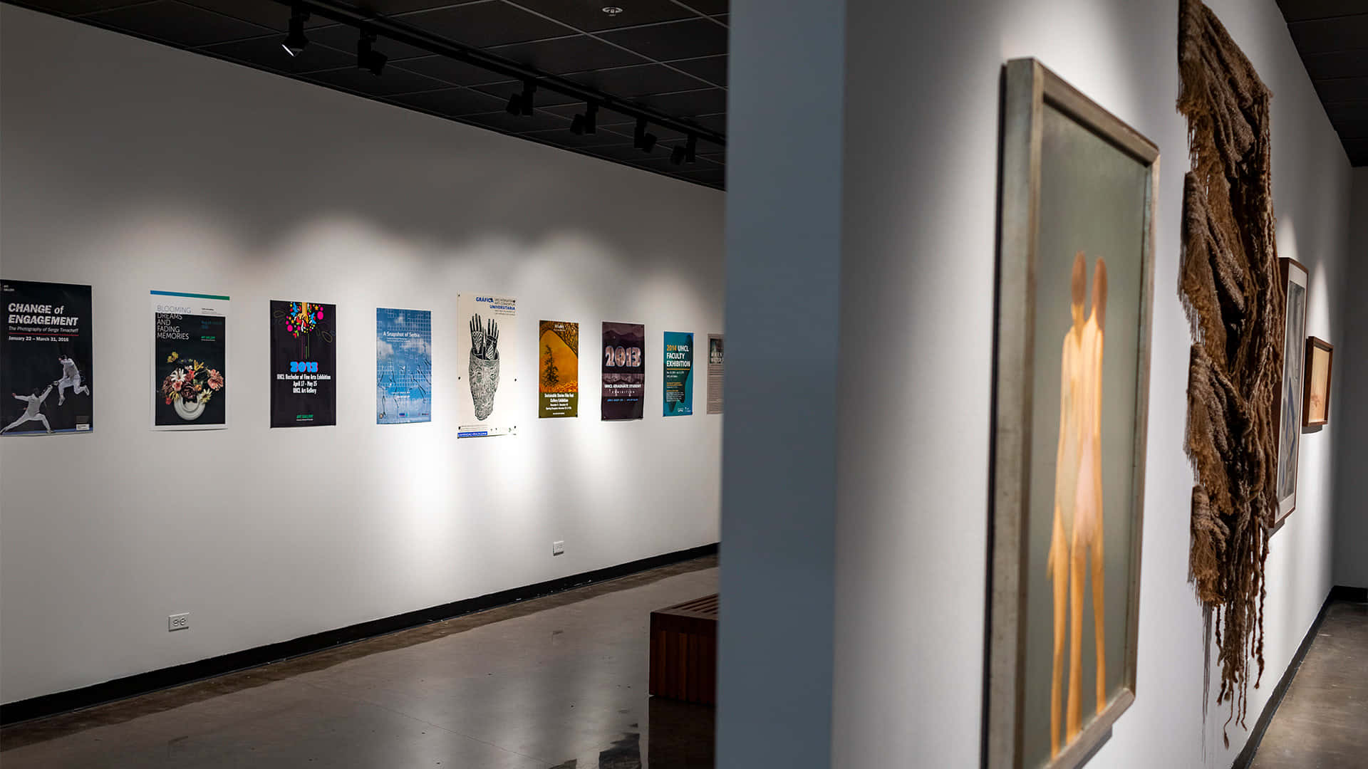 伊斯蘭藝術博物館內部展覽廳 壁紙 — 現代藝術畫廊走廊，白色牆壁上掛有聚光燈照明的海報和裱框雕塑，黑色天花板燈光下。