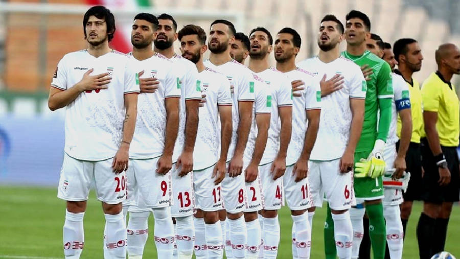 Iran 桌布 壁紙 — 伊朗足球隊身穿白色球衣，在國歌奏起時莊嚴地站在綠色球場上，雙手放在心口。