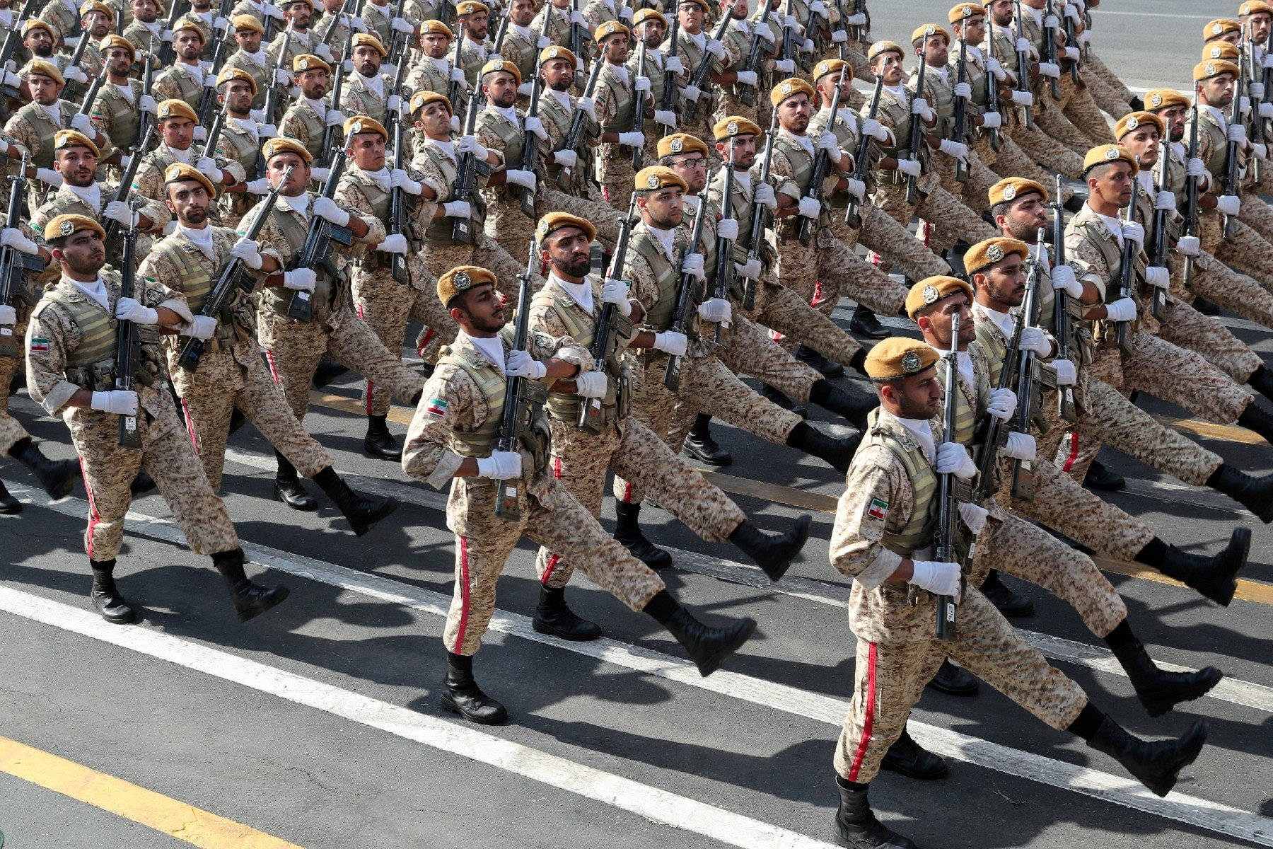 伊朗軍隊行軍 壁紙 — 一排排身穿制服的士兵以完美的隊形在鋪砌的道路上行進，手持步槍，神情專注。