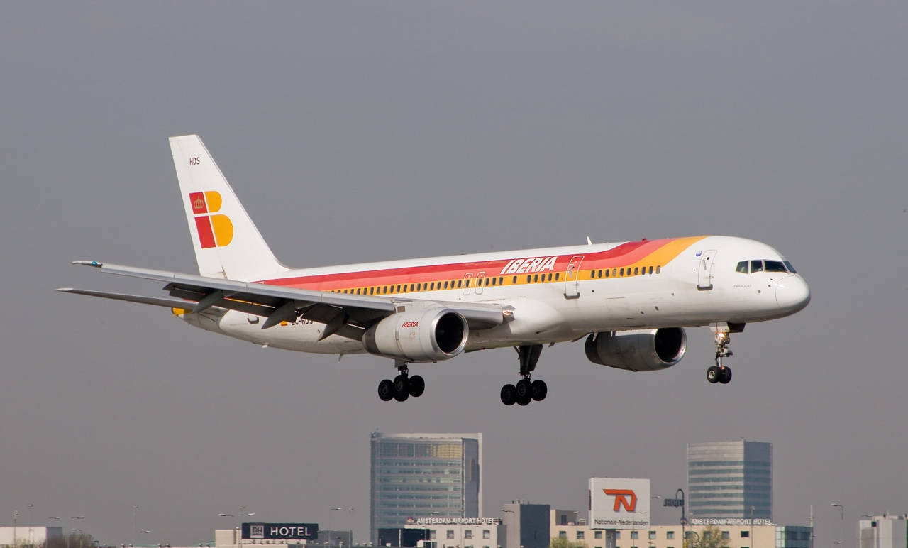 伊比利亞航空飛機在朦朧的日子降落在城市建築物上空。