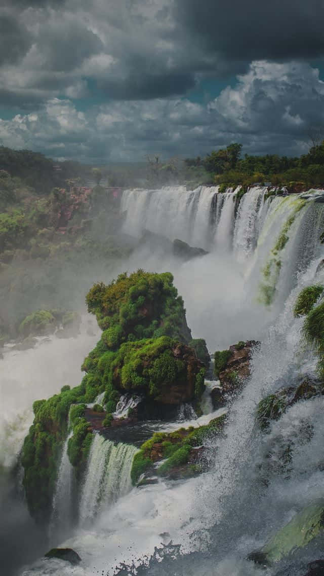 強勁的瀑布在暴風雨的天空下流過長滿苔蘚的懸崖。