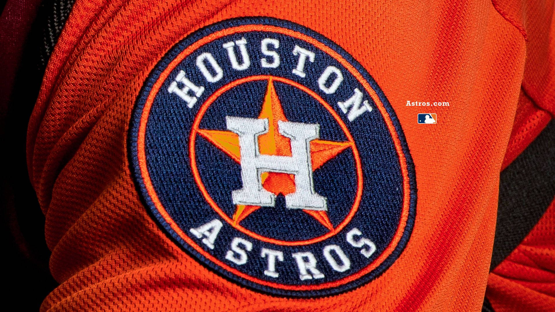 休士頓太空人隊隊徽織補特寫 壁紙 — Houston Astros 棒球球衣標誌的特寫，繡在充滿活力的橙色布料上。