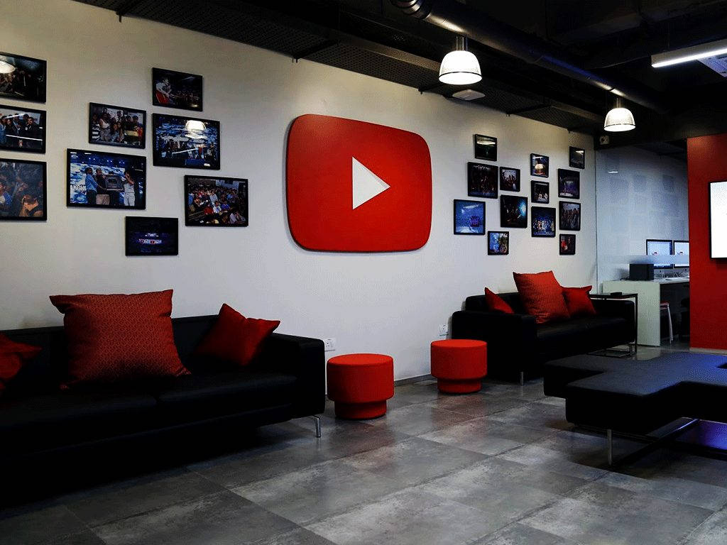 YouTube 辦公室休息區，配有黑色沙發、紅色靠墊，牆上有大標誌。