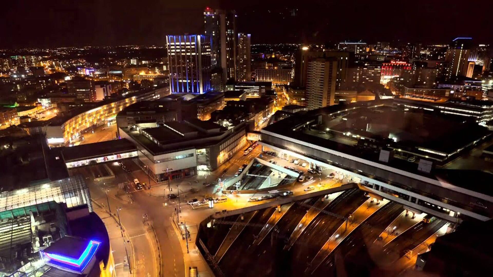 伯明翰市夜景 壁紙 — 充滿活力的城市景觀夜間鳥瞰圖，下方有發光的摩天大樓和明亮的街道。