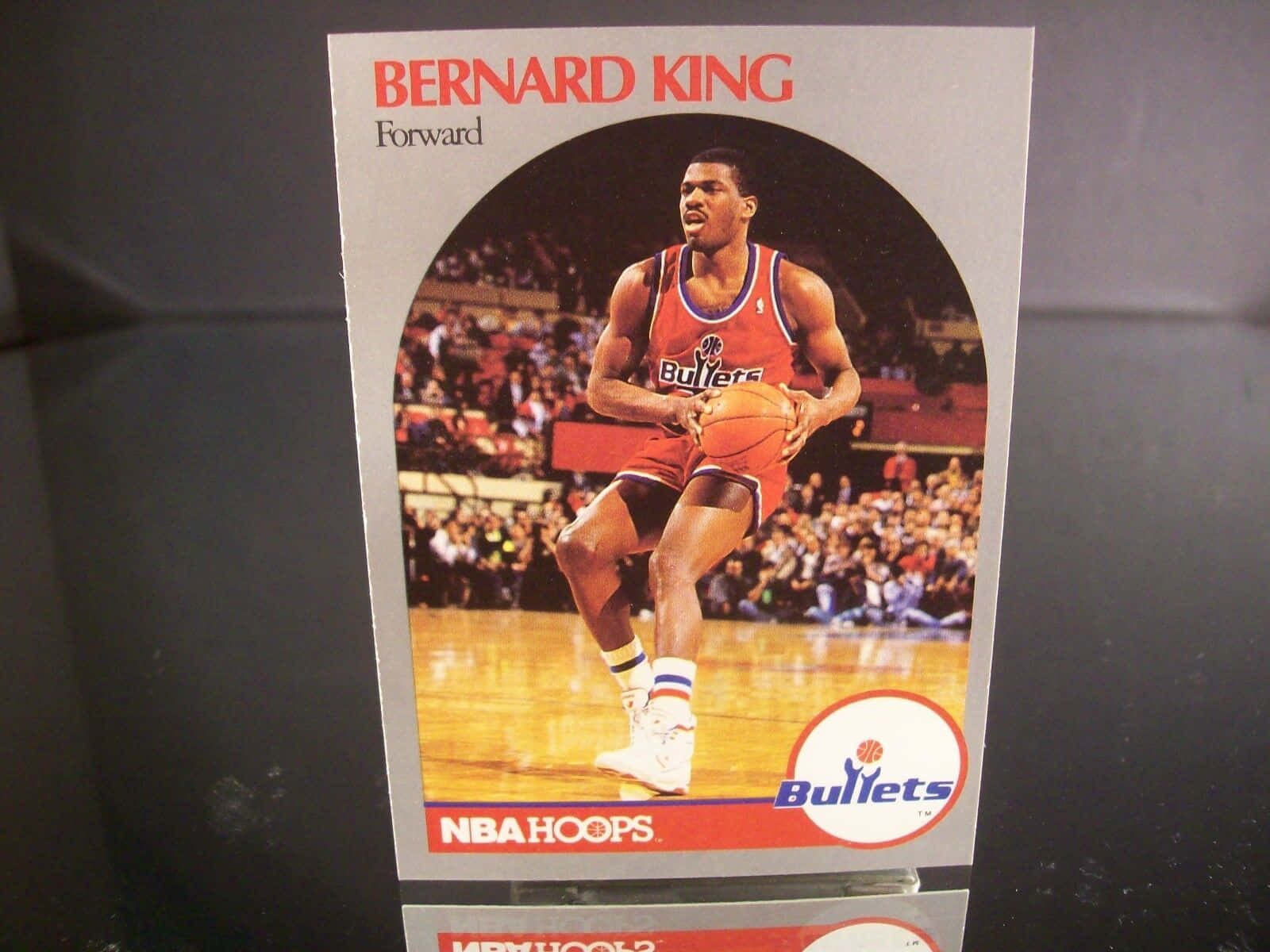 伯納德·金 NBA Hoops 收藏卡 壁紙 — 復古NBA Hoops球星卡，展示Bernard King身穿紅色子彈隊球衣在硬木球場上運球，背景有觀眾。