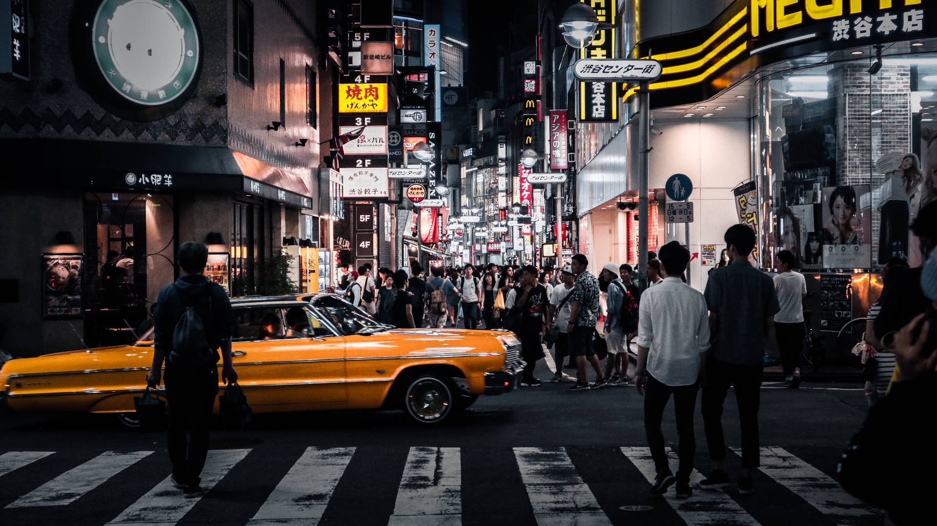 黃色復古汽車在霓虹燈下穿越夜晚東京繁忙的街道。