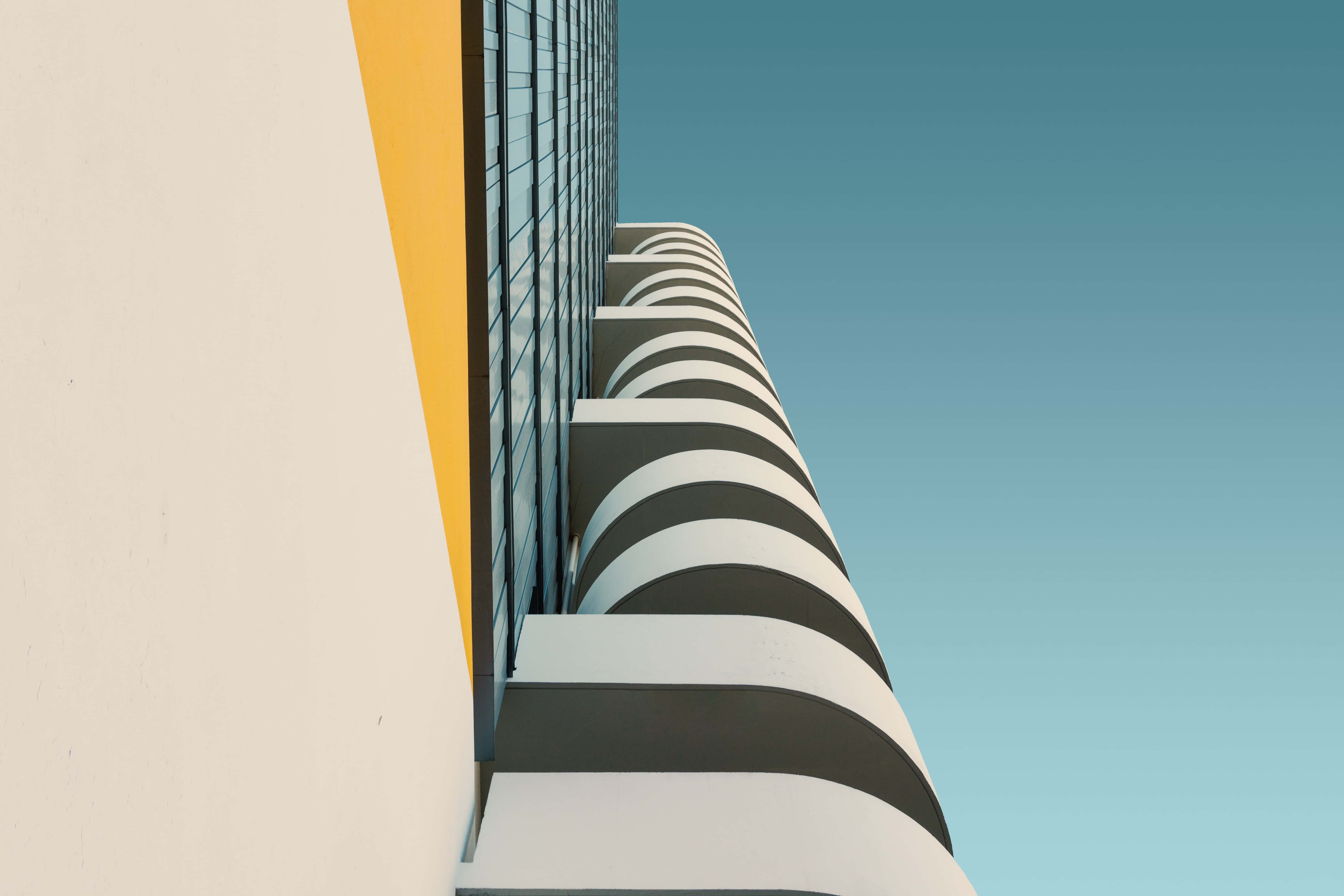 Modernism 桌布 壁紙 — 低角度拍攝現代建築，大膽的黑白曲線陽台襯托著清澈的藍天。
