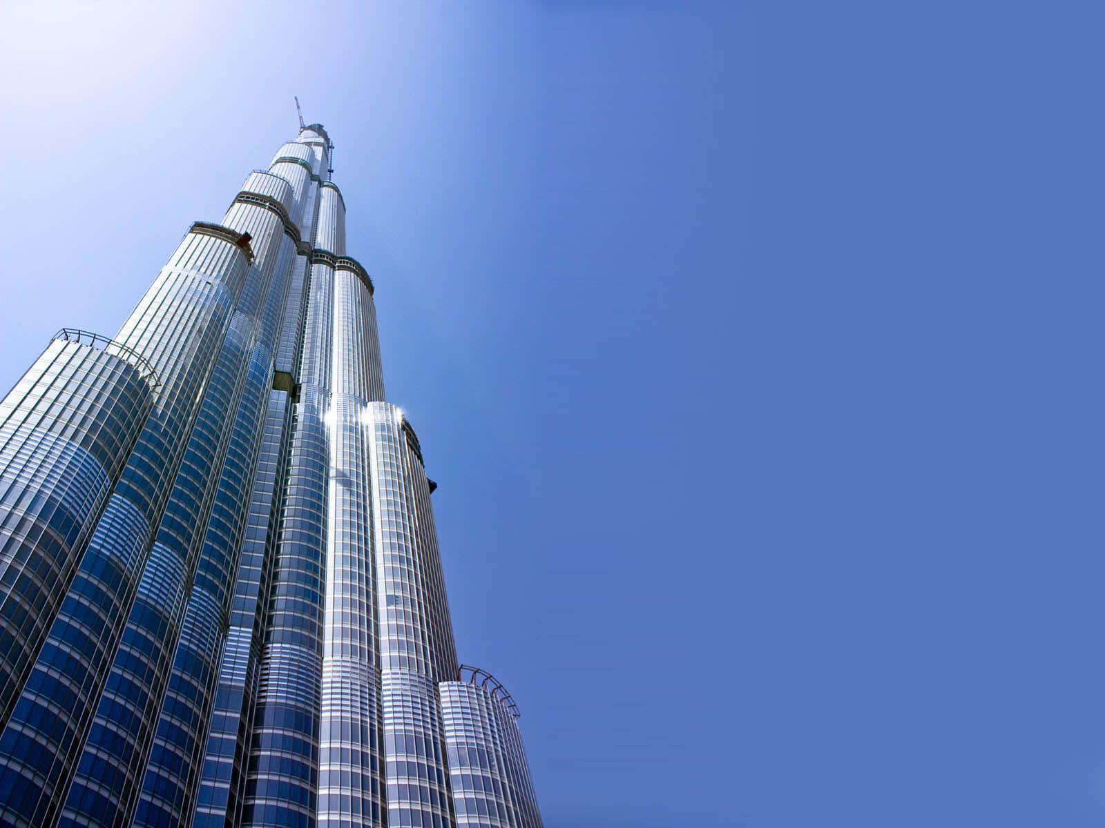 Burj Khalifa 桌布 壁紙 — 低角度觀看哈利法塔，其玻璃和鋼製尖頂刺穿清澈的藍天。