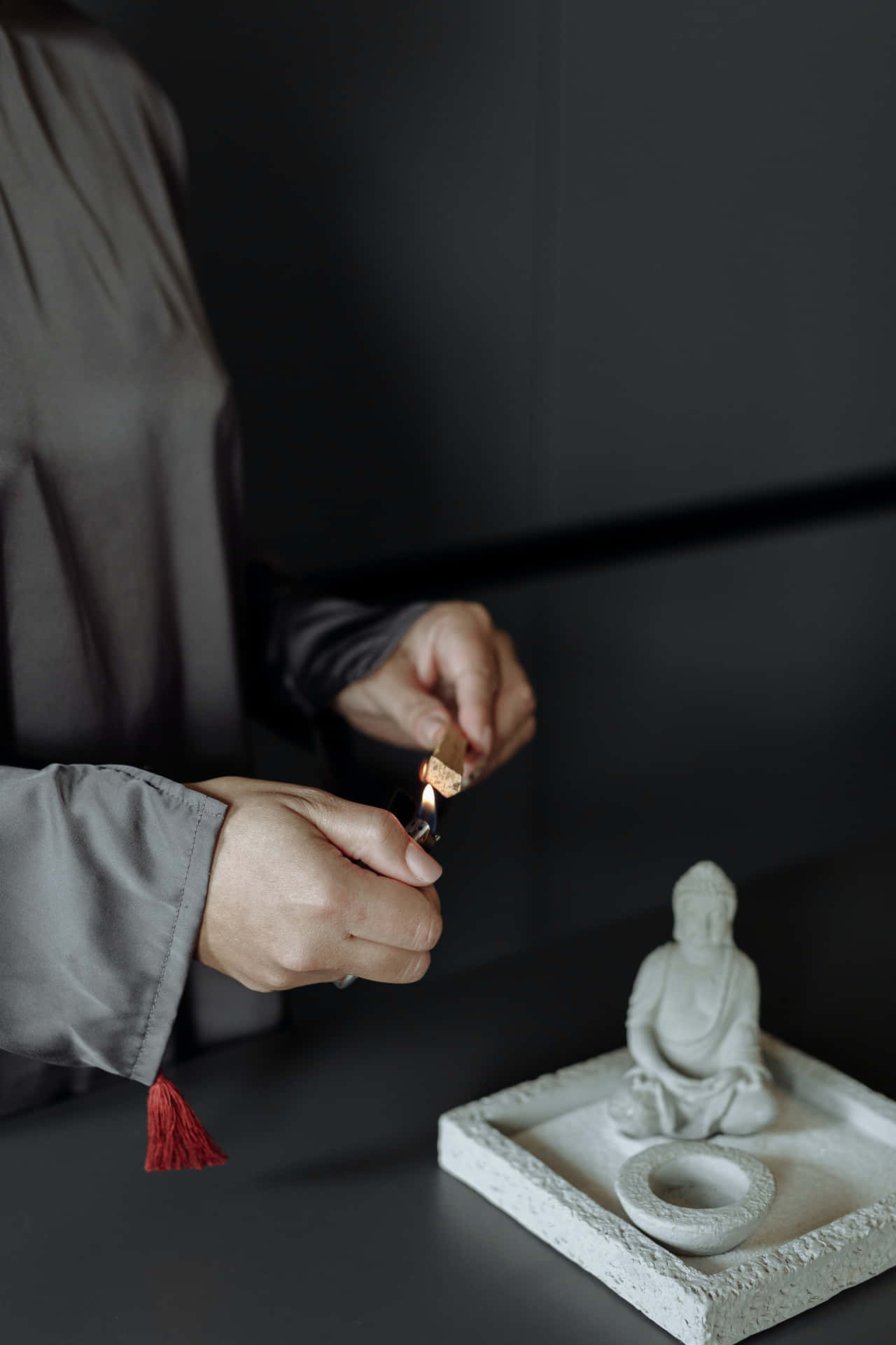 在簡約環境中，有人在佛像附近點燃蠟燭