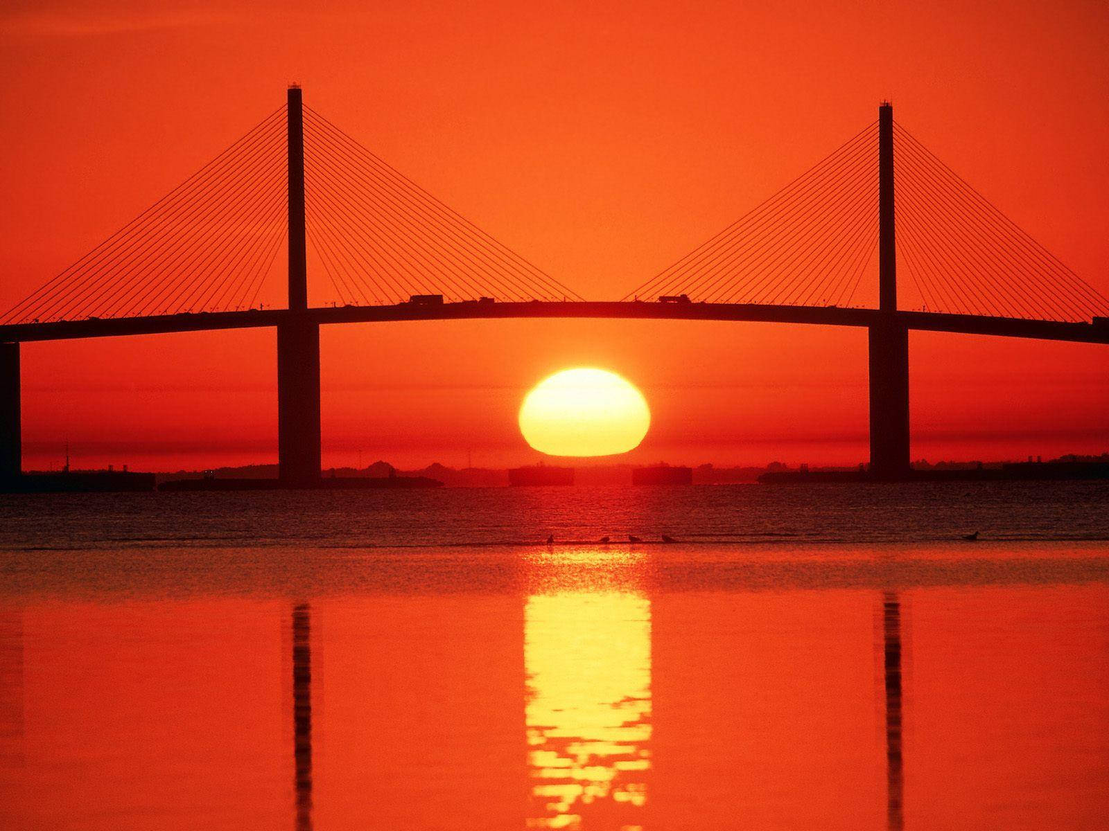 夕陽下的橋樑，橙色天空和水面倒影