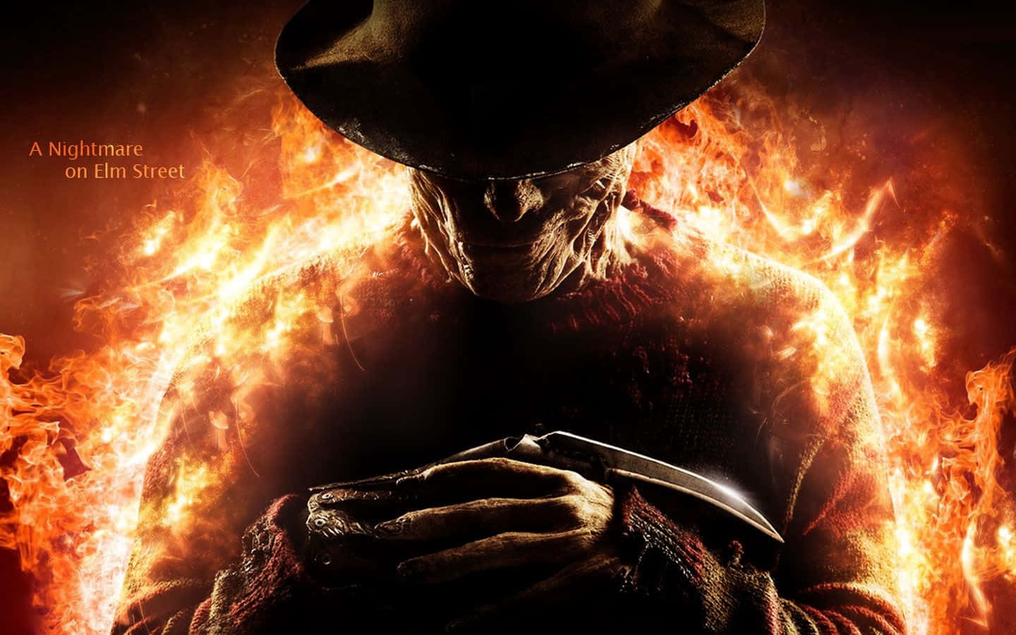 Freddy Krueger 桌布 壁紙 — 佛萊迪·克魯格從咆哮的火焰中出現，手持刀刃，以威脅性的特寫鏡頭呈現。
