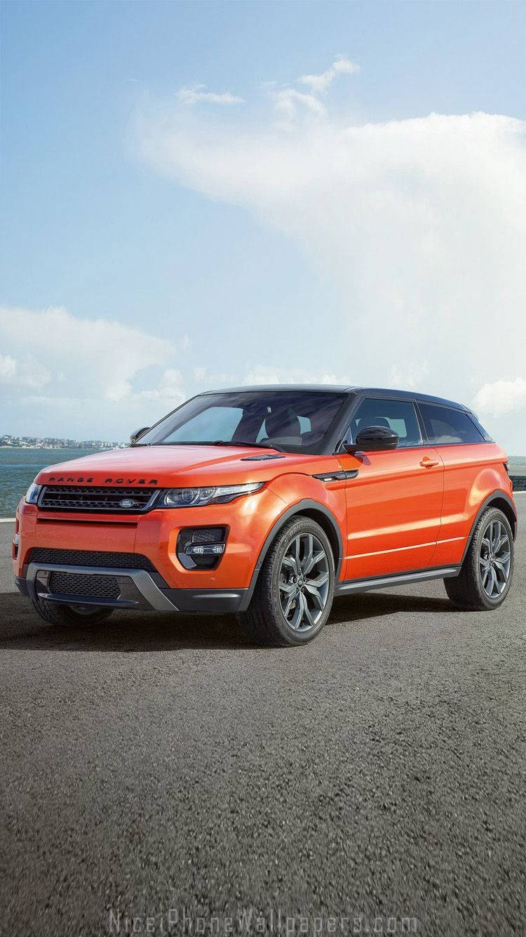 橙色Range Rover Evoque停泊在瀝青路上，藍天白雲。