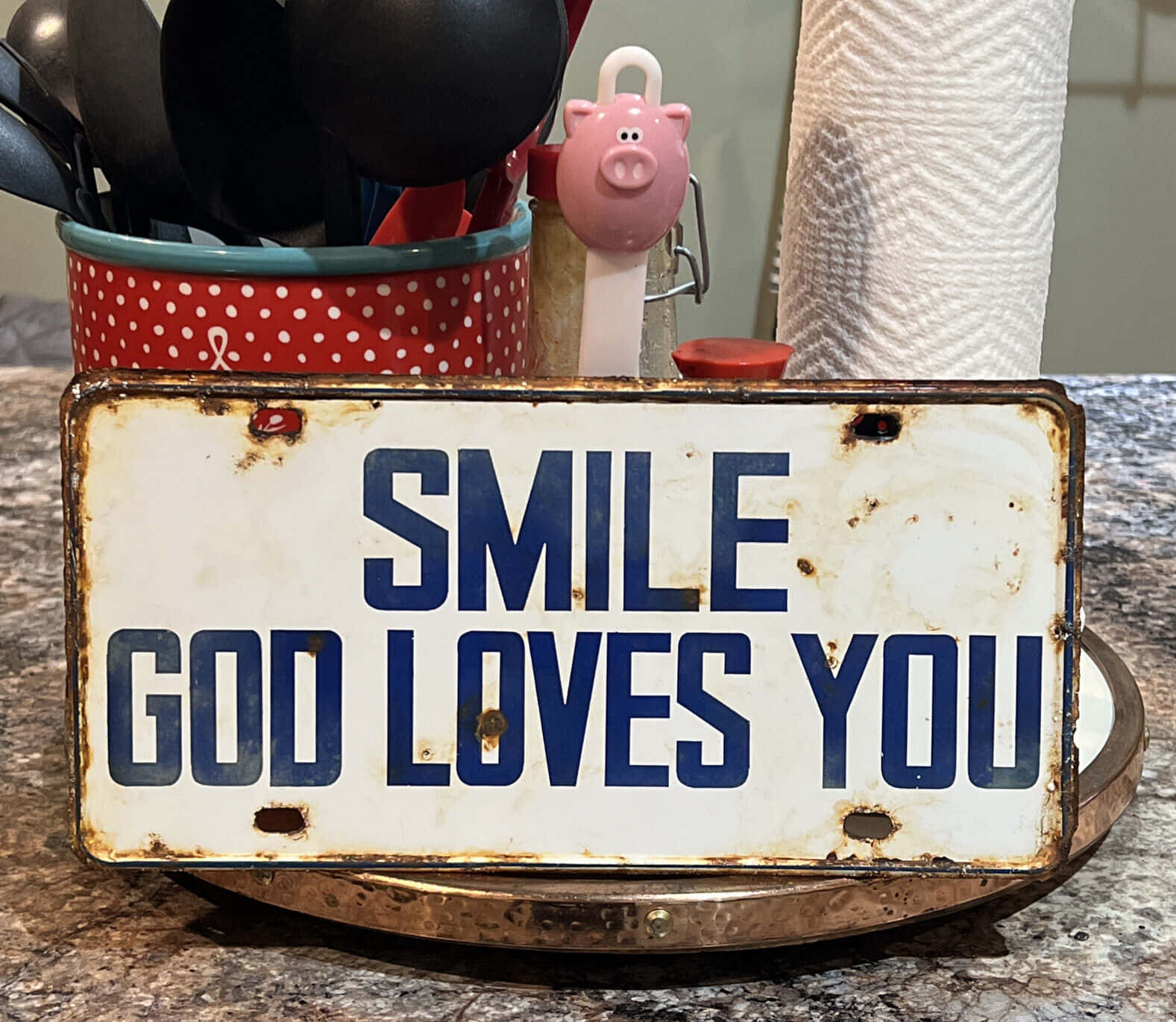 廚房檯面上寫有「Smile God Loves You」的質樸金屬標牌。